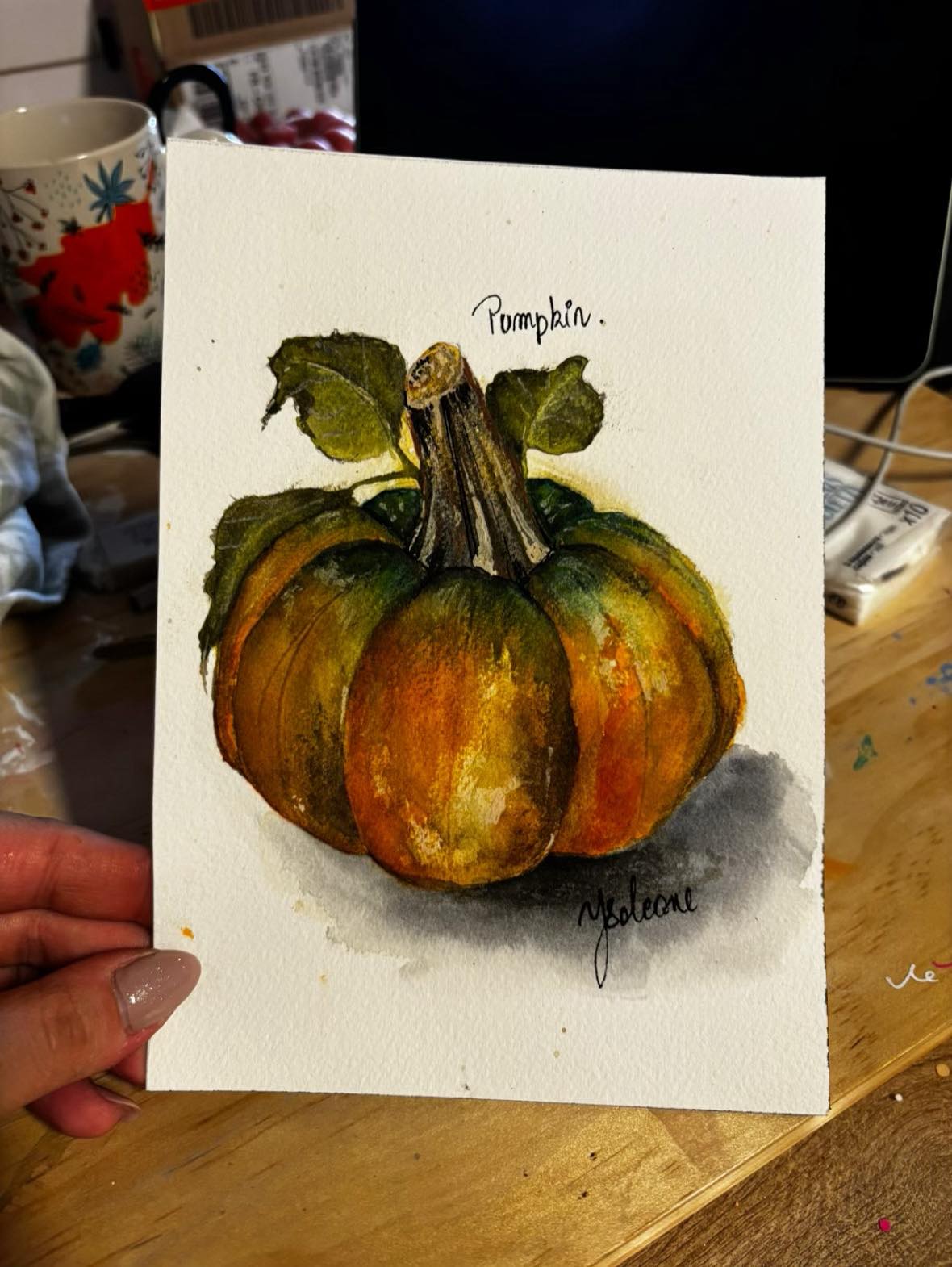 Aquarelle — une citrouille aux côtes vertes et orangées sur fond blanc, ombre portée discrète à droite.